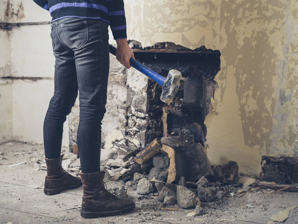 Woman opening up fireplace with sledge hammer